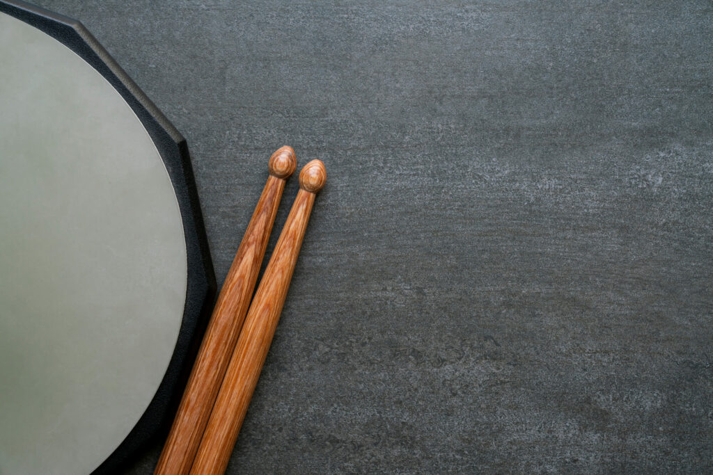 Gray practice pad with wooden drumsticks.