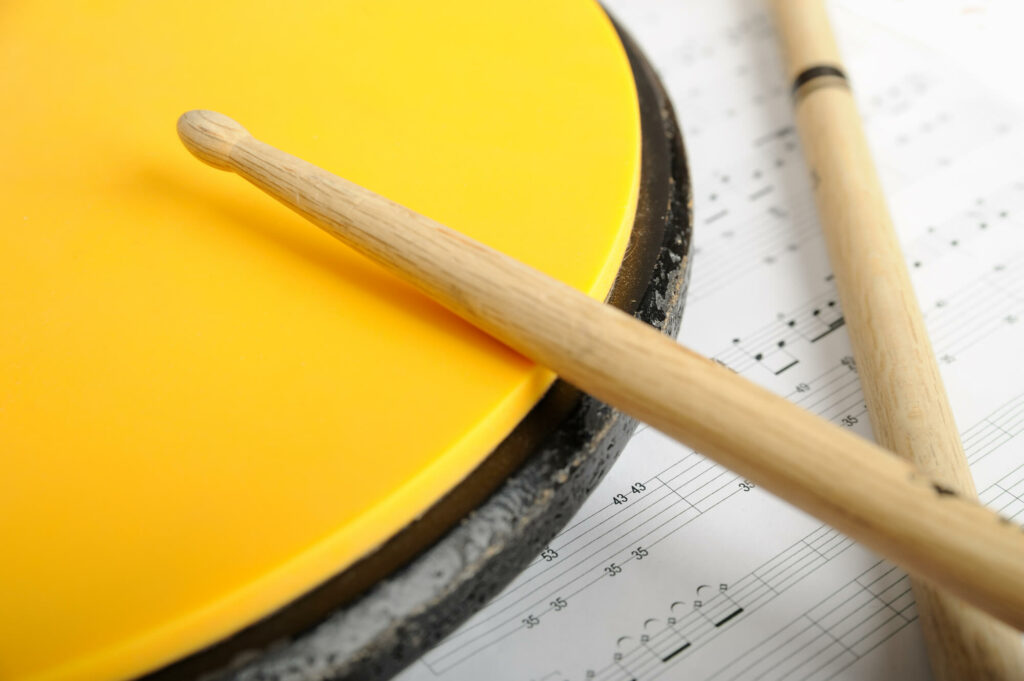 Round, yellow practice pad with drumsticks.